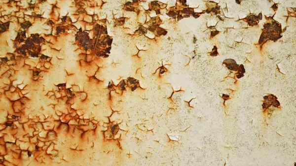 Тріщини та іржа на металевій поверхні, що ілюструють відкриття про здатність металу до самовідновлення.